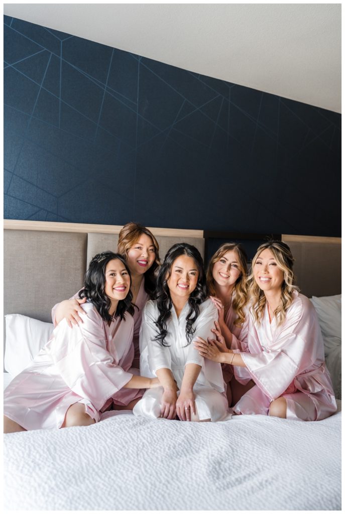 Bride smiling with Bridesmaid on Hotel bed before Sequoyah Country Club Wedding