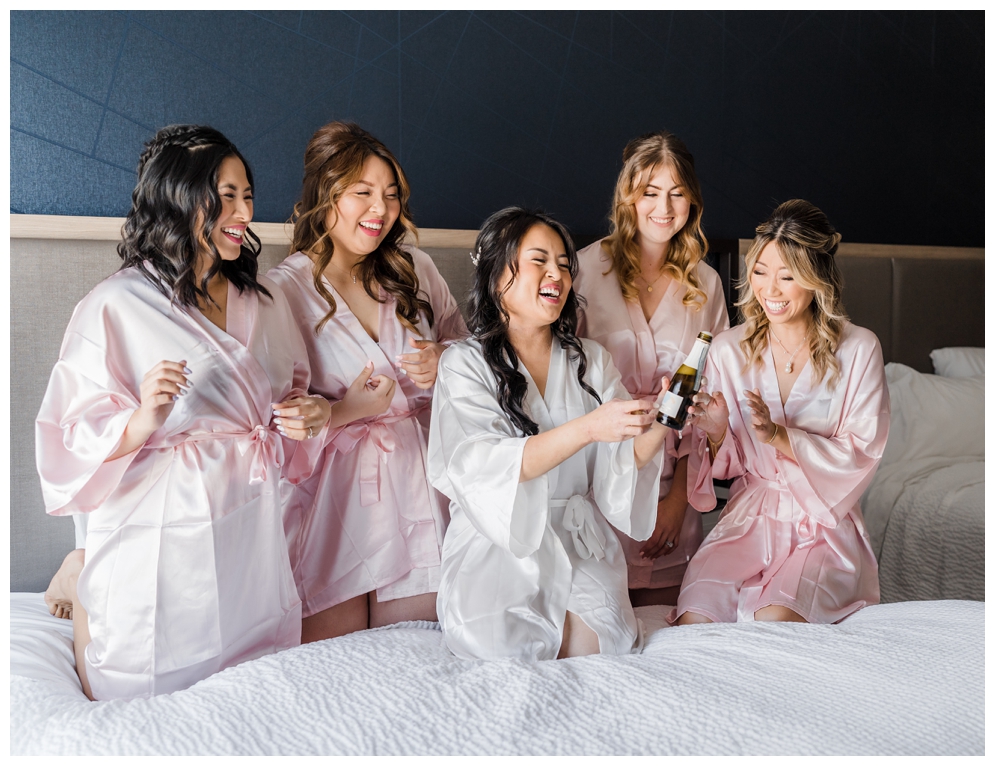 Bride and Bridesmaid on Hotel Bed Popping Champagne before Sequoyah Country Club